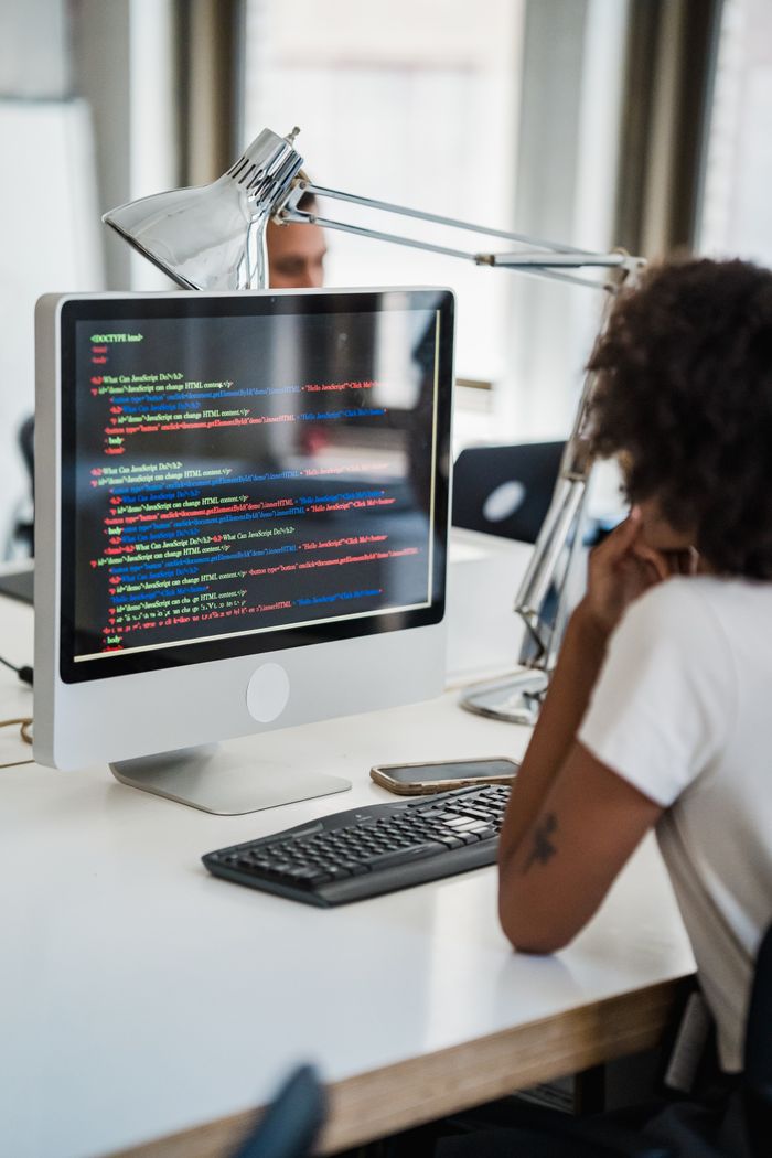 Mastering the First Impression: Your intriguing post title goes here A female professional focused on coding at her office desk with a desktop computer.
